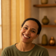 Headshot portrait of a happy, diverse woman in her 30s smiling confidently, with a soft, warm-toned background.